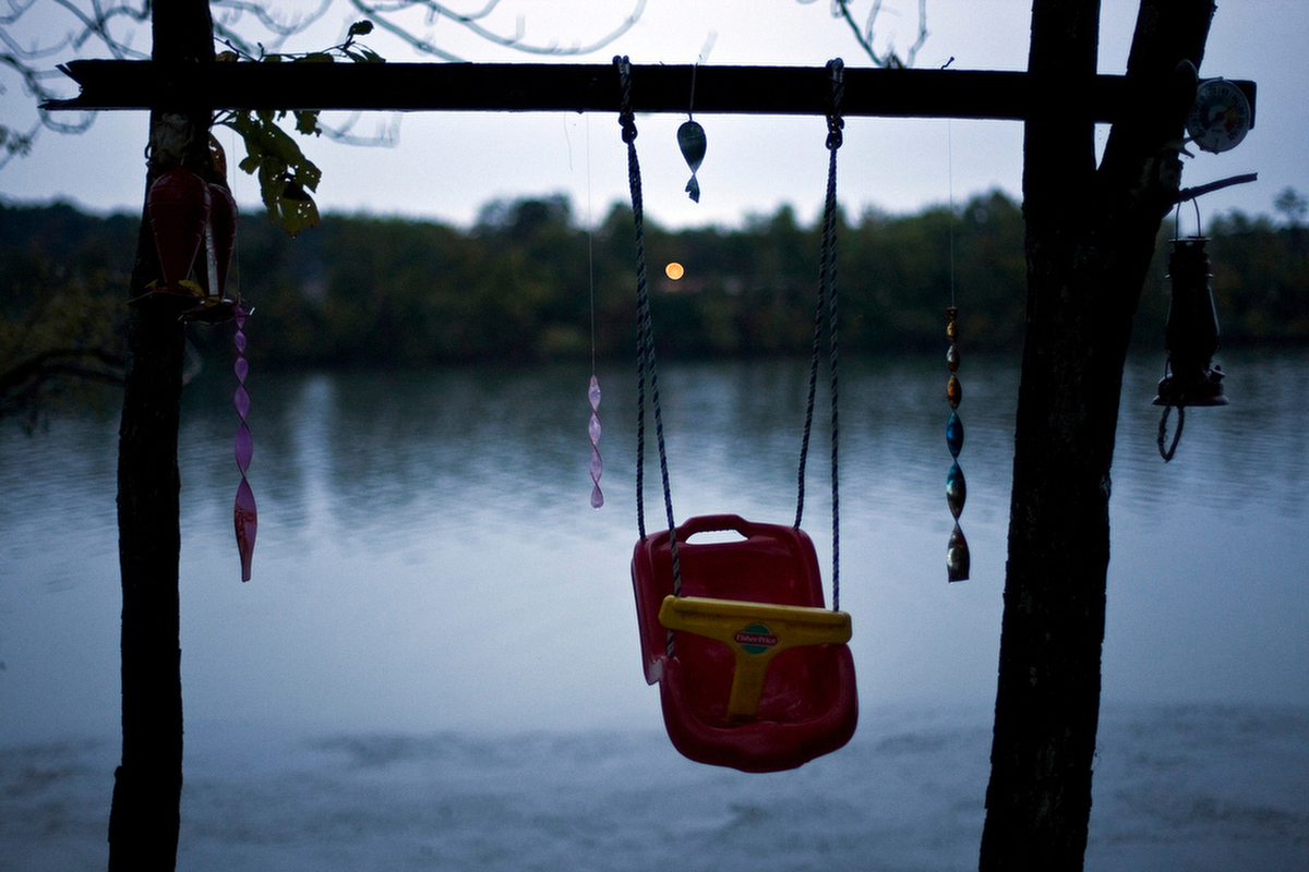 An infant's swing sits unused outside of Travis's parents' camper alongside the Ohio River.
